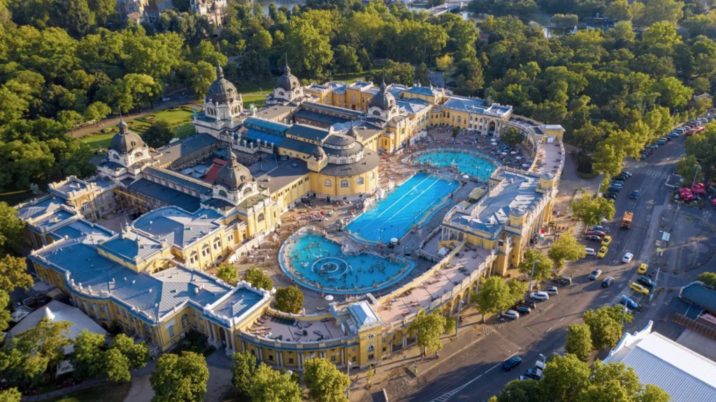 Aerial daytime view of Széchenyi Thermal Bath surrounded by greenery in Budapest City Park